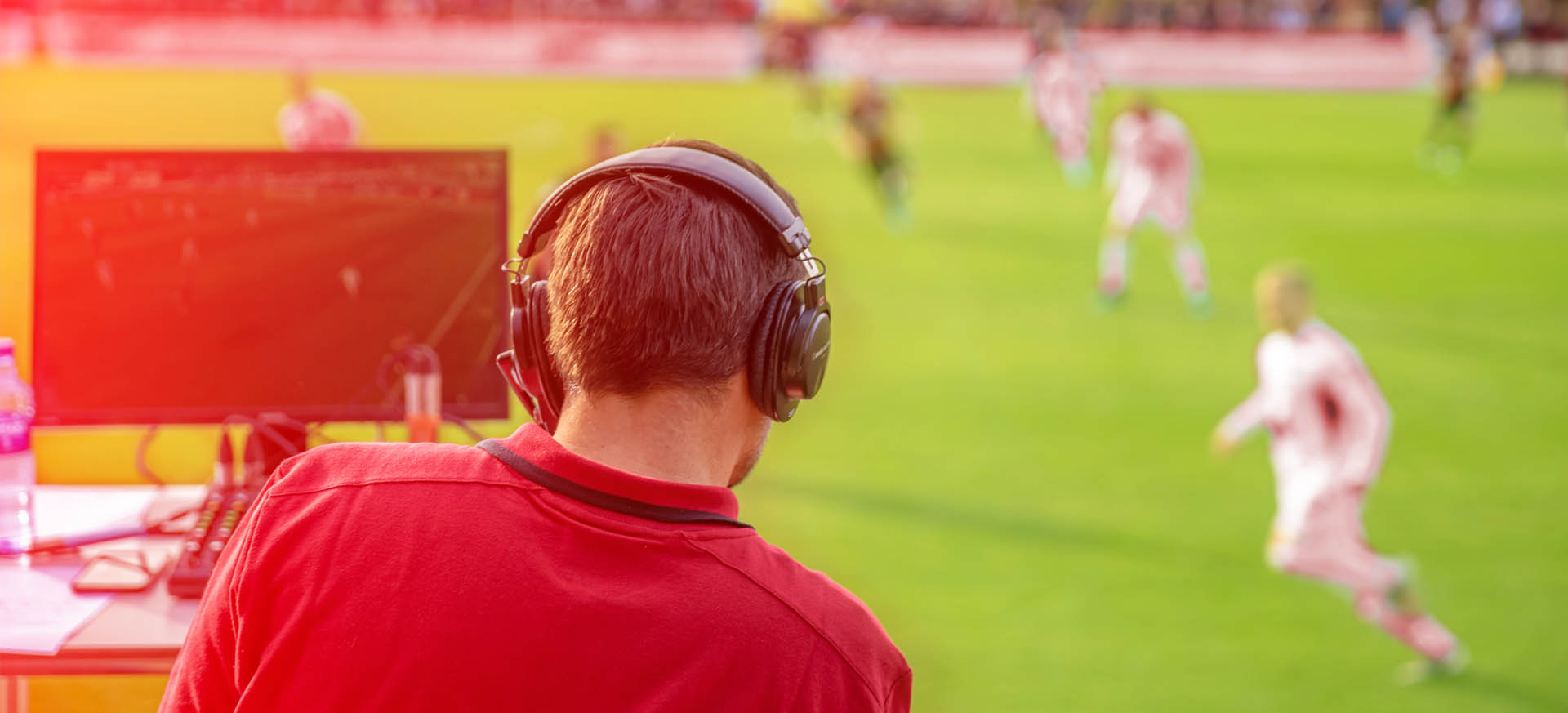Sportjournalist mit Kopfhörern am Spielfeldrand